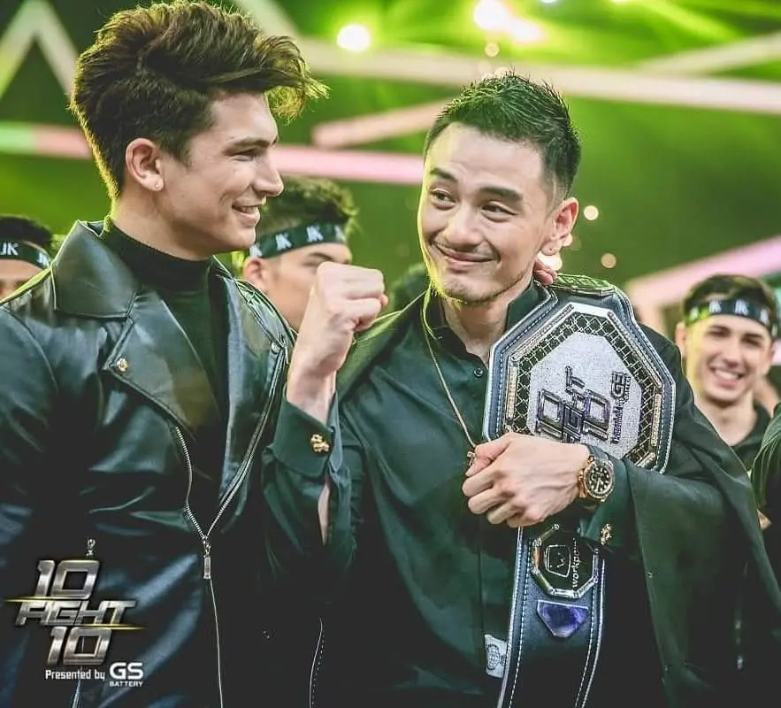Antoine Pinto beside a Team Black contestant holding the championship belt